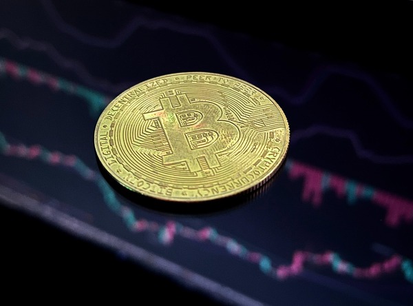 Bitcoin coin displayed beside a live cryptocurrency exchange dashboard